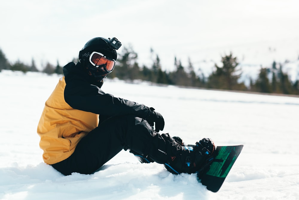 Persona con chaqueta amarilla y pantalones negros montando en snowboard