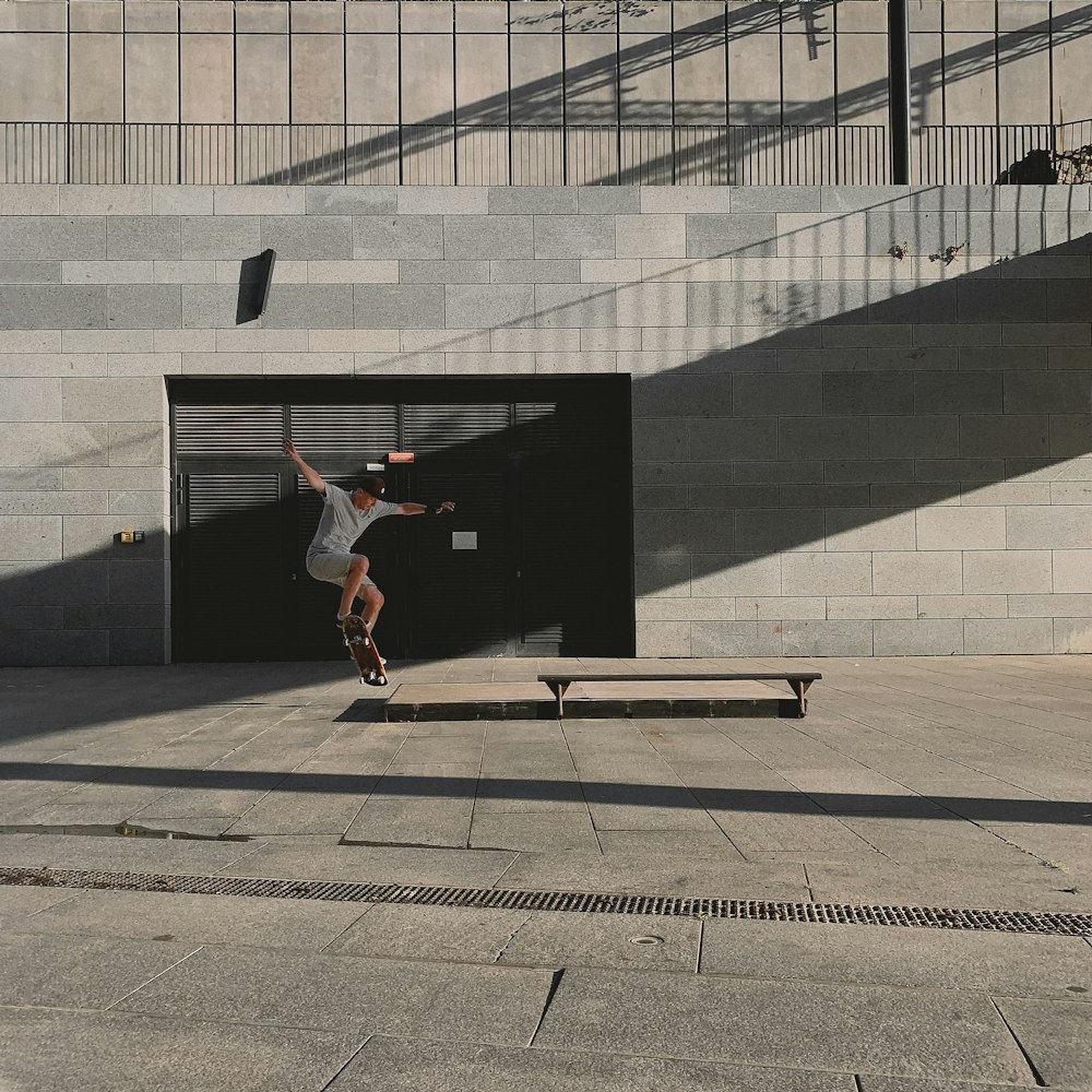 man in black t-shirt and brown pants jumping on brown wooden skateboard during daytime