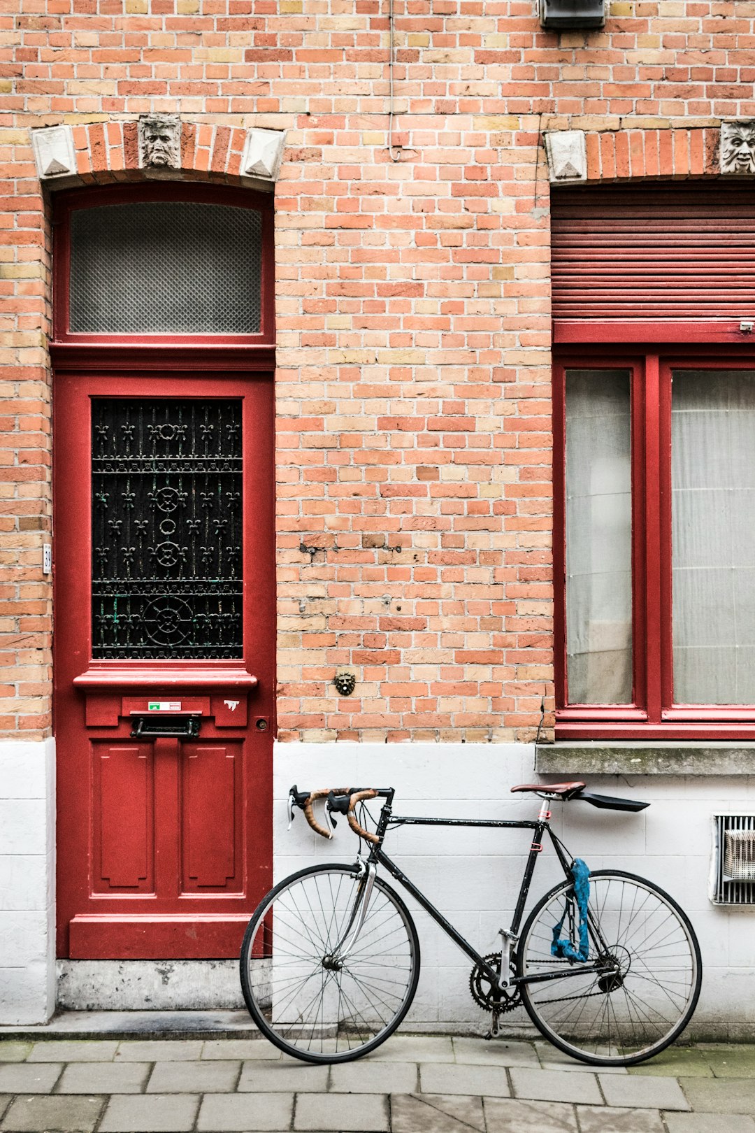 blue city bike parked beside red wooden door