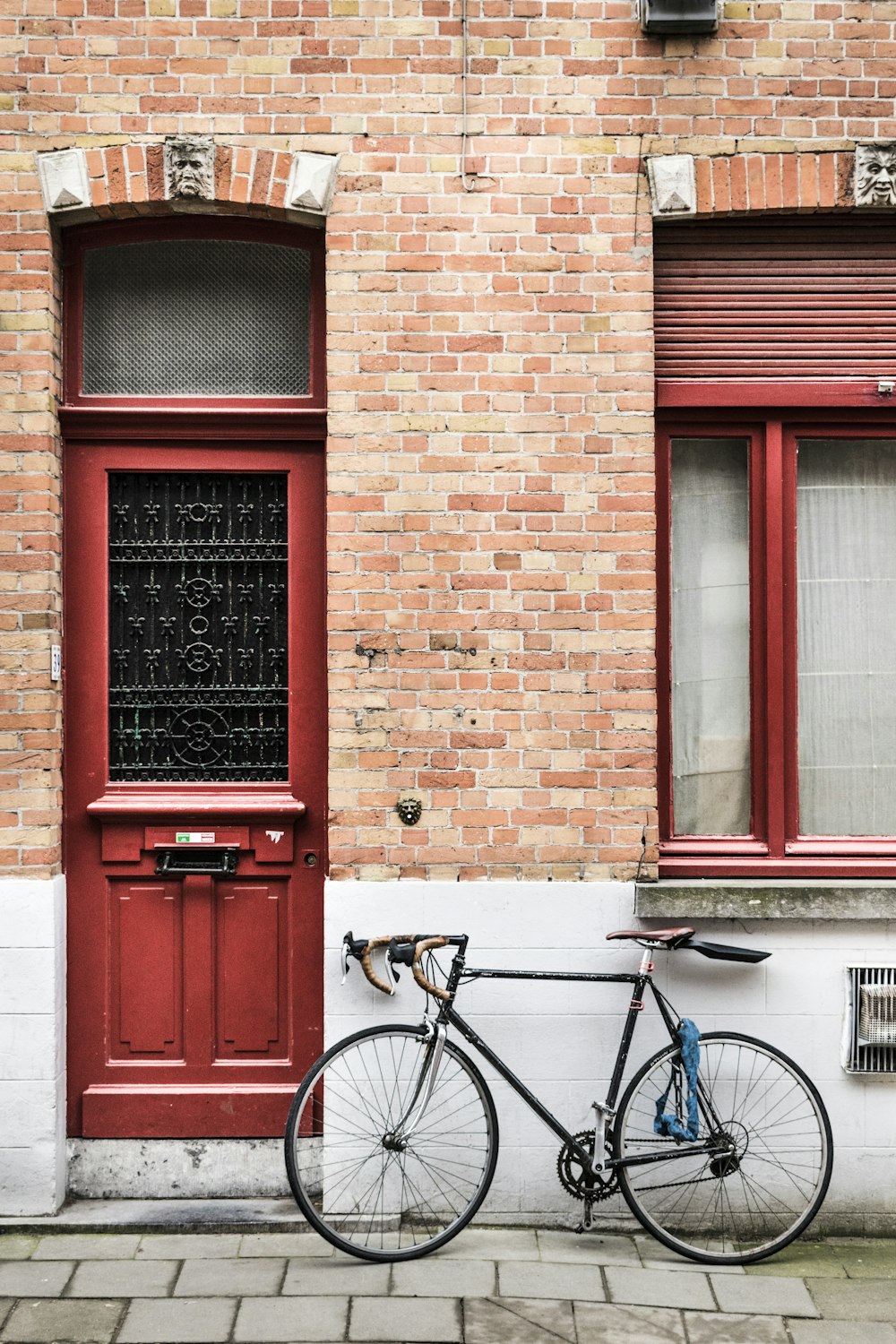 blue city bike parked beside red wooden door