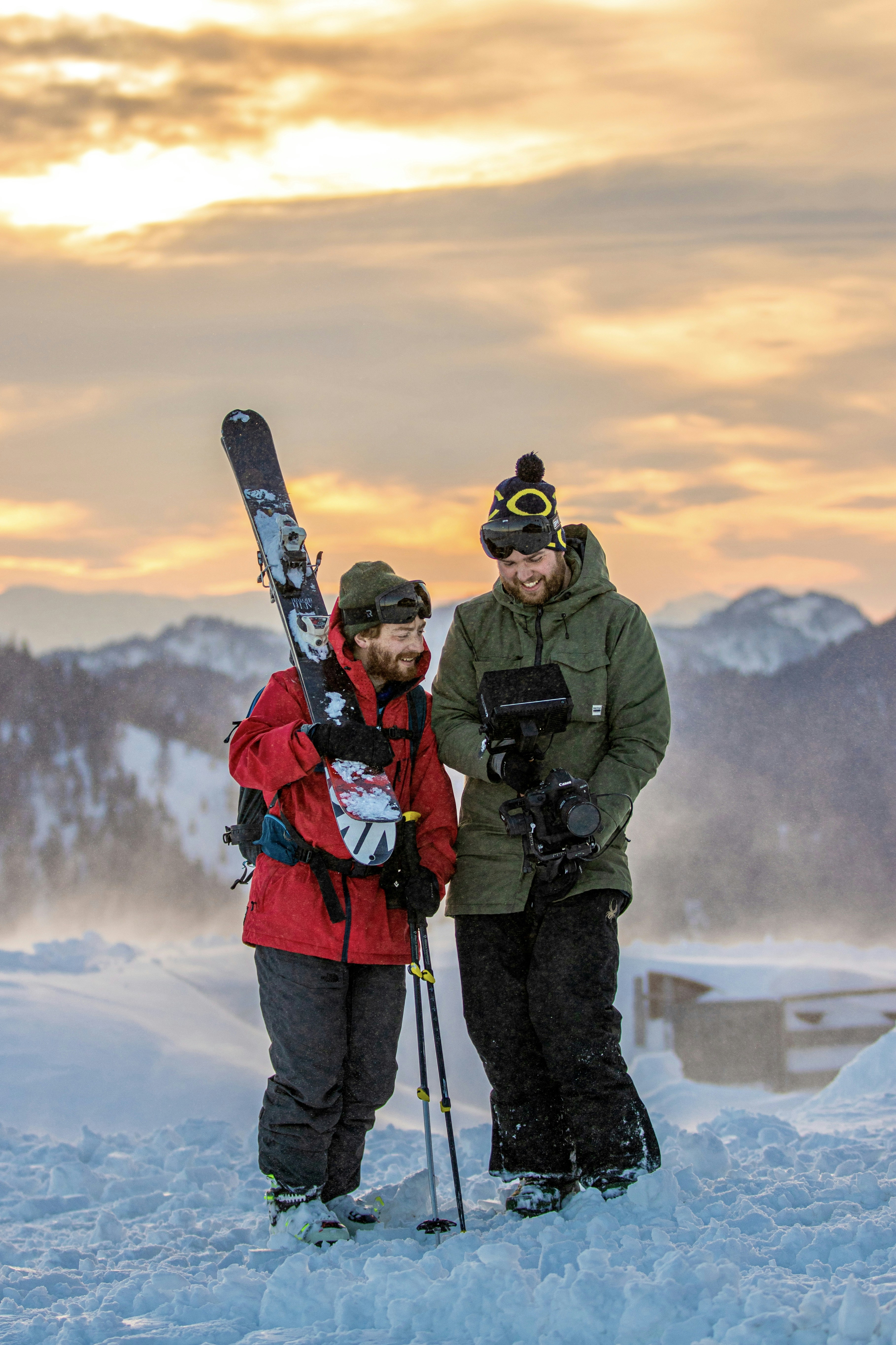 a couple of men standing next to each other holding skis