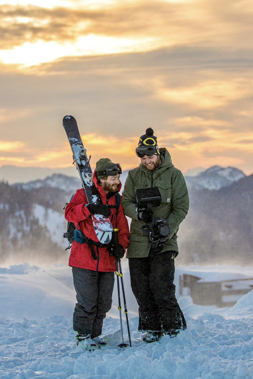 a couple of men standing next to each other holding skis