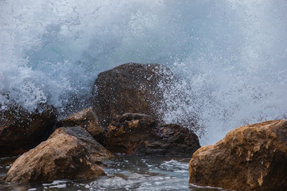 water waves hitting rocks during daytime