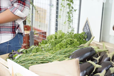A chef selecting fresh vegetables from a rustic wooden crate at a local farmers market.