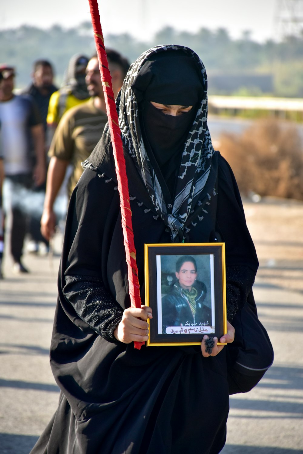 woman in black hijab holding gold framed photo