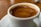 Close-up of freshly brewed coffee in a ceramic cup with mountain scenery blurred in the background.