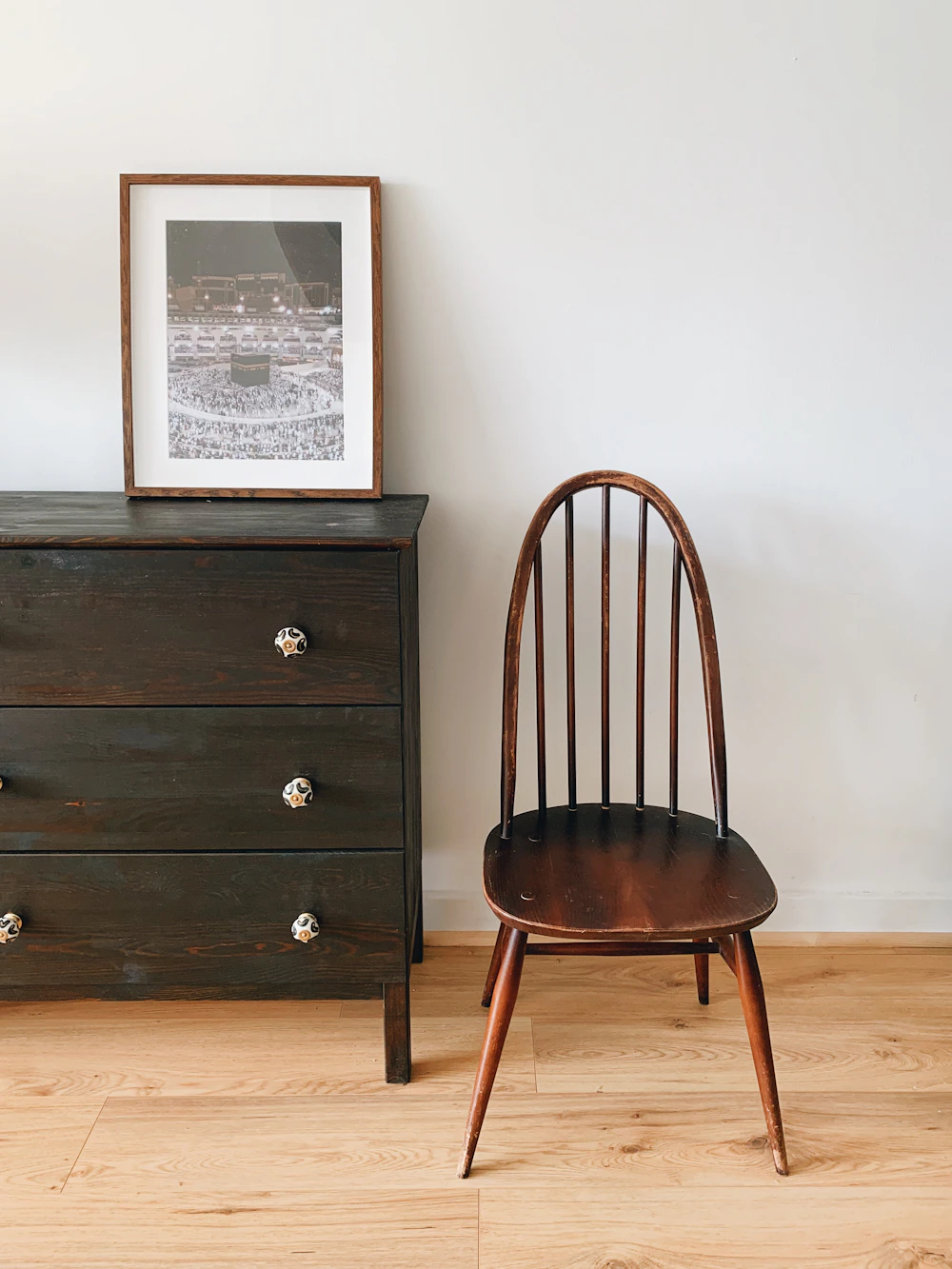 A bright room corner with a vintage armchair, a floor lamp and a stack of books on a side table