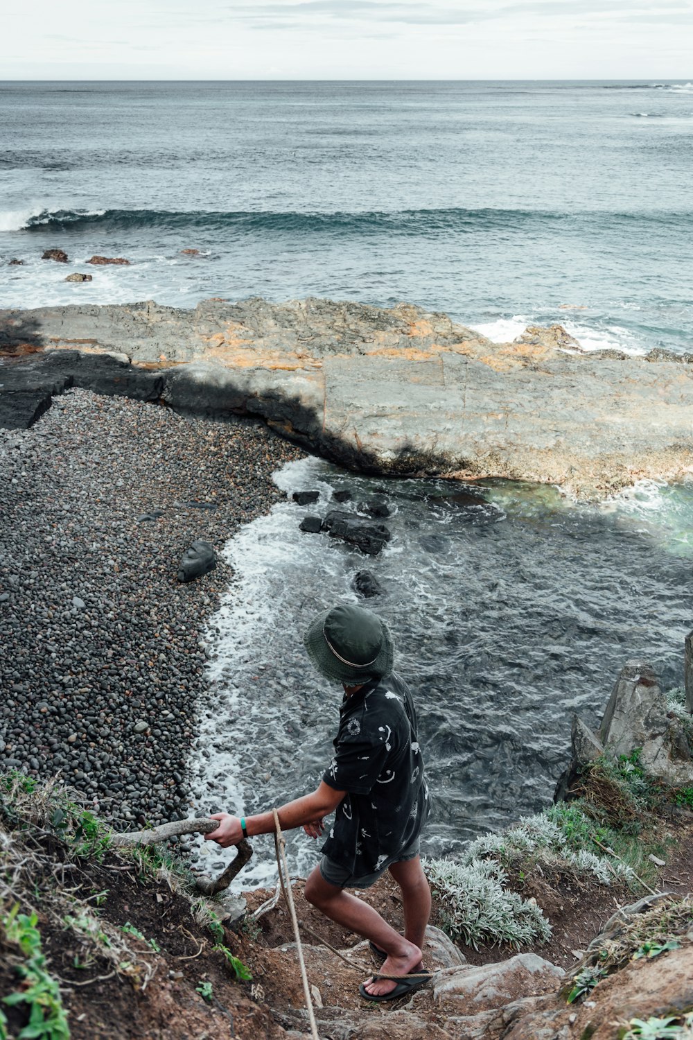 man in black t-shirt and black backpack sitting on rocky shore during daytime