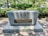 A memorial plaque set on a large stone block, surrounded by trees and greenery. The plaque contains a menorah symbol and text dedicating the site to James Edward Oglethorpe for the Savannah Jewish Community. Small stones are placed on top of the memorial.