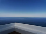 Balcony view from a hotel room showing the sparkling ocean and clear blue sky.