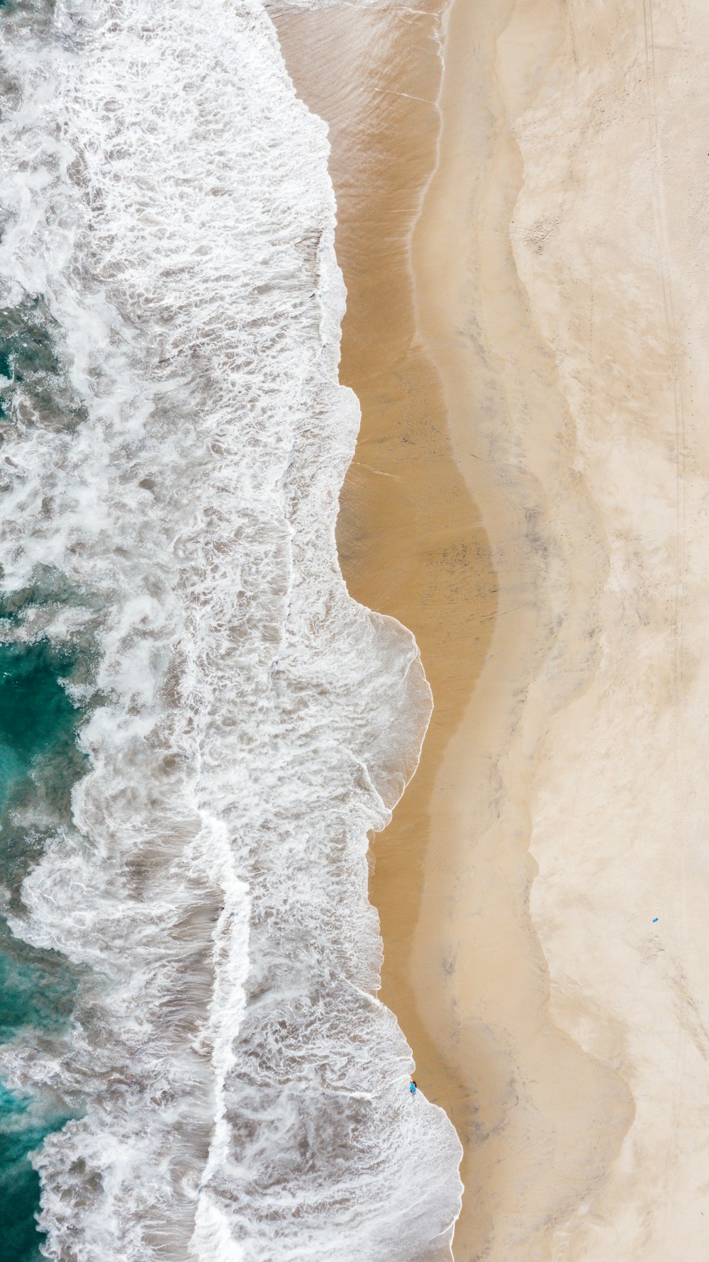 aerial view of ocean waves crashing on shore during daytime