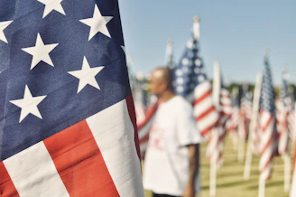 Veteran standing in a memorial of USA flags, link to Coverage Catalysts article for Veterans