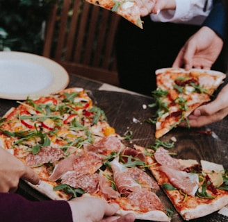 person holding pizza with cheese and green leaves