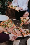 person holding pizza with cheese and green leaves