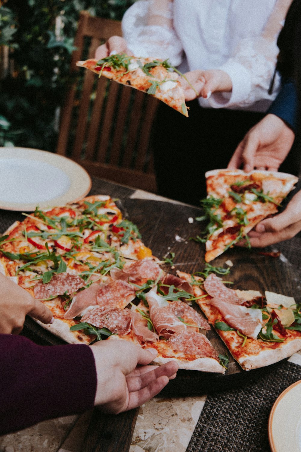 Persona sosteniendo pizza con queso y hojas verdes