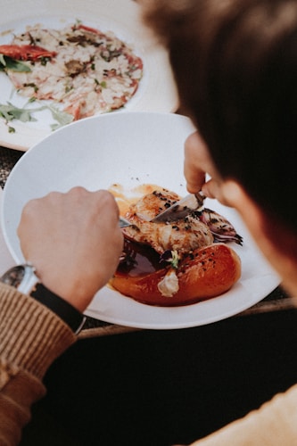 person holding sliced of tomato on white ceramic plate