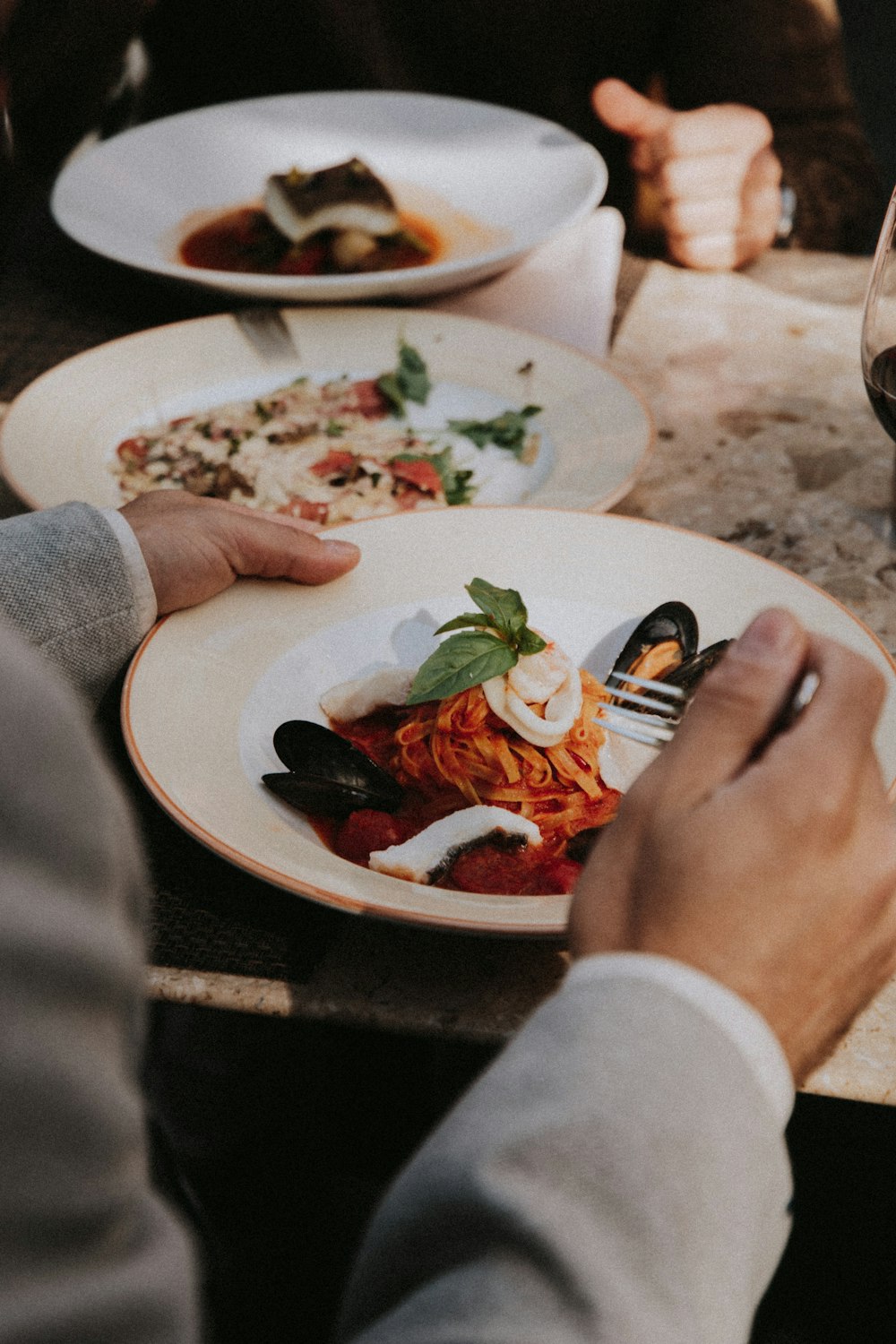 person holding stainless steel fork and knife slicing red and green vegetable on white ceramic plate