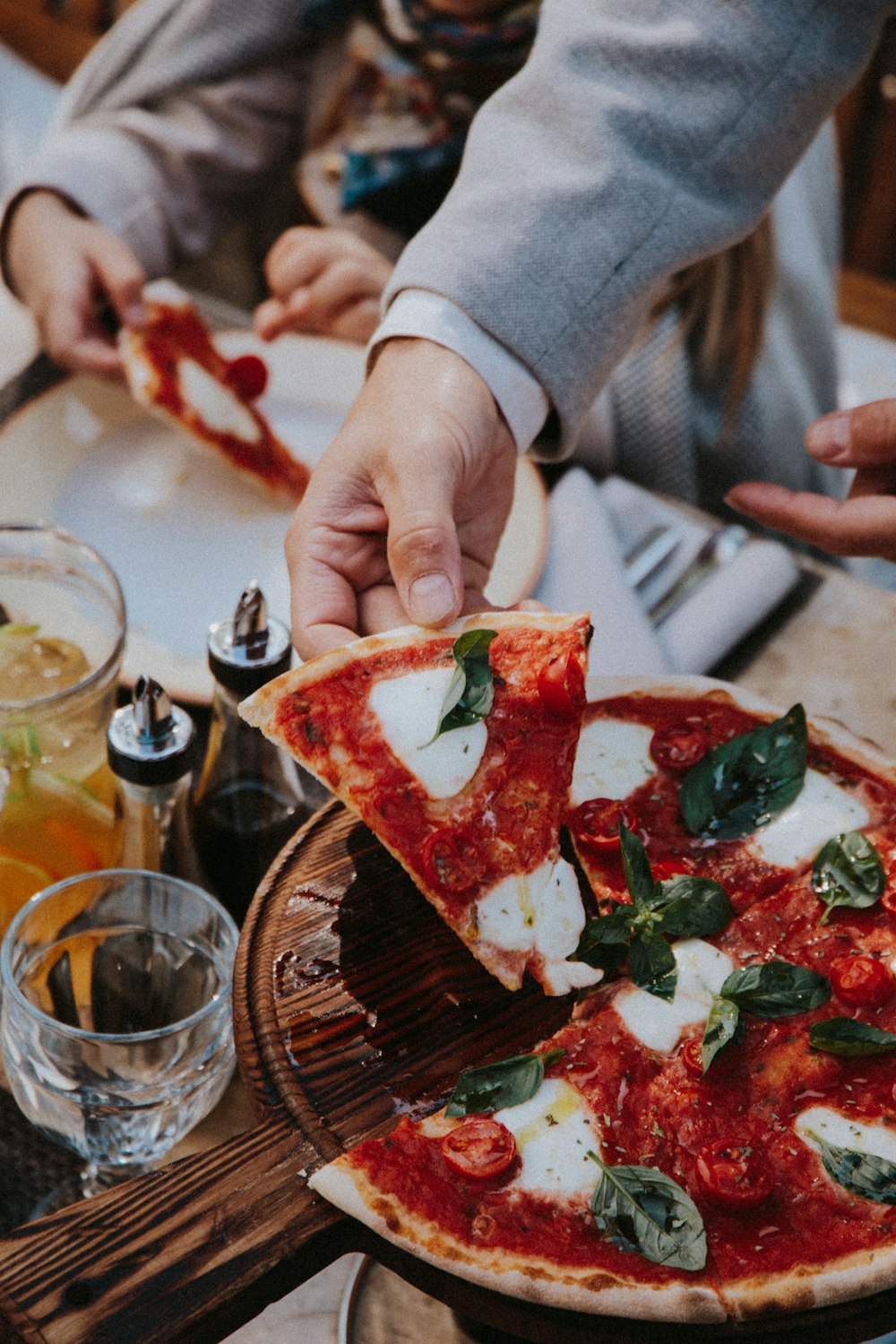 person holding sliced pizza on brown wooden table