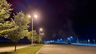 Nighttime shot of a parking lot with reflective striping glowing under streetlights