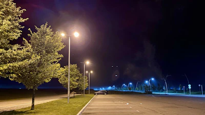 Parking lot at dusk showing rows of green-accented schön area lights providing safe, clear visibility.