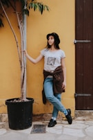 Young person wearing a beige t-shirt with the Unidos Streetwear logo, standing against a sleek black wall.
