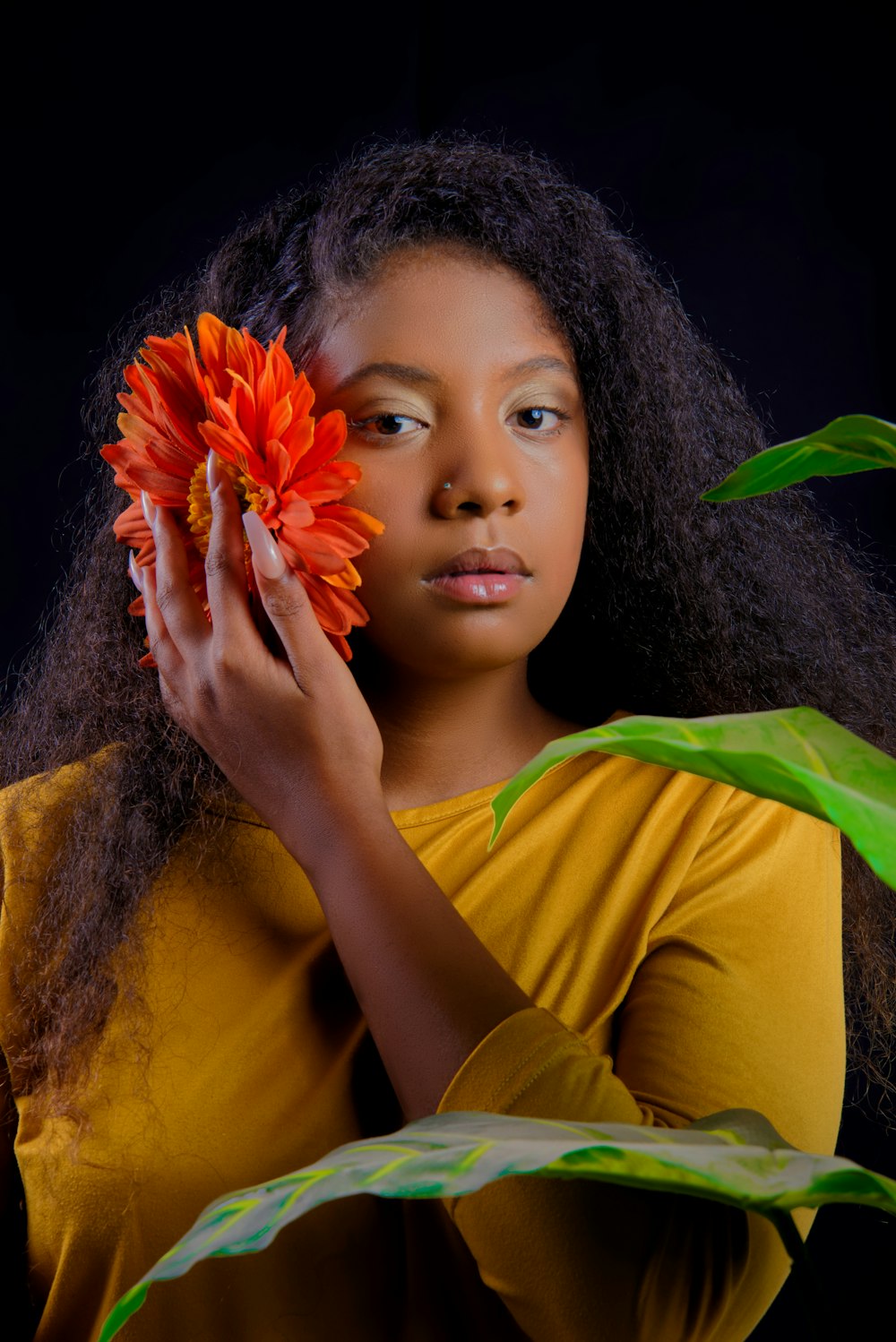 girl in yellow shirt holding red flower