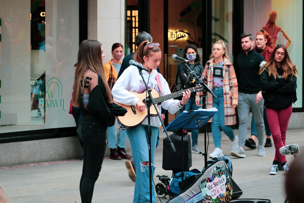 man in black suit playing guitar beside woman in black long sleeve shirt