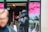 A person dressed as a statue in a metallic, stone-like costume is posing in front of a vibrant storefront display. The person appears to be giving a thumbs-up gesture. There are blurred figures and a display of a cosmetics brand in the background, featuring bright pink and white colors.
