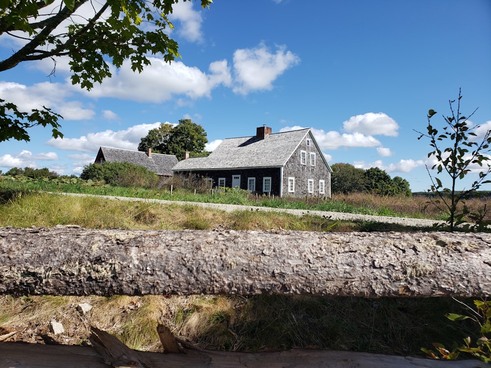 brown wooden log on green grass field near brown wooden house under blue sky during daytime