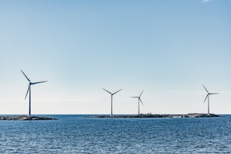 A panoramic view of offshore wind turbines spinning gracefully under a bright sky.