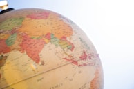 A globe displaying a section of Asia, including countries such as China, India, and Indonesia. The image is well-lit with sunlight coming in from the top right corner, creating a bright and warm atmosphere. The names of the countries and geographical borders are clearly visible, highlighted in various colors.