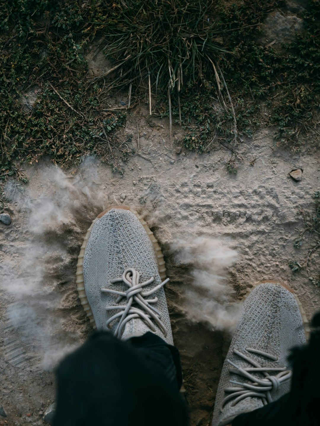 person in gray and white sneakers standing on gray sand