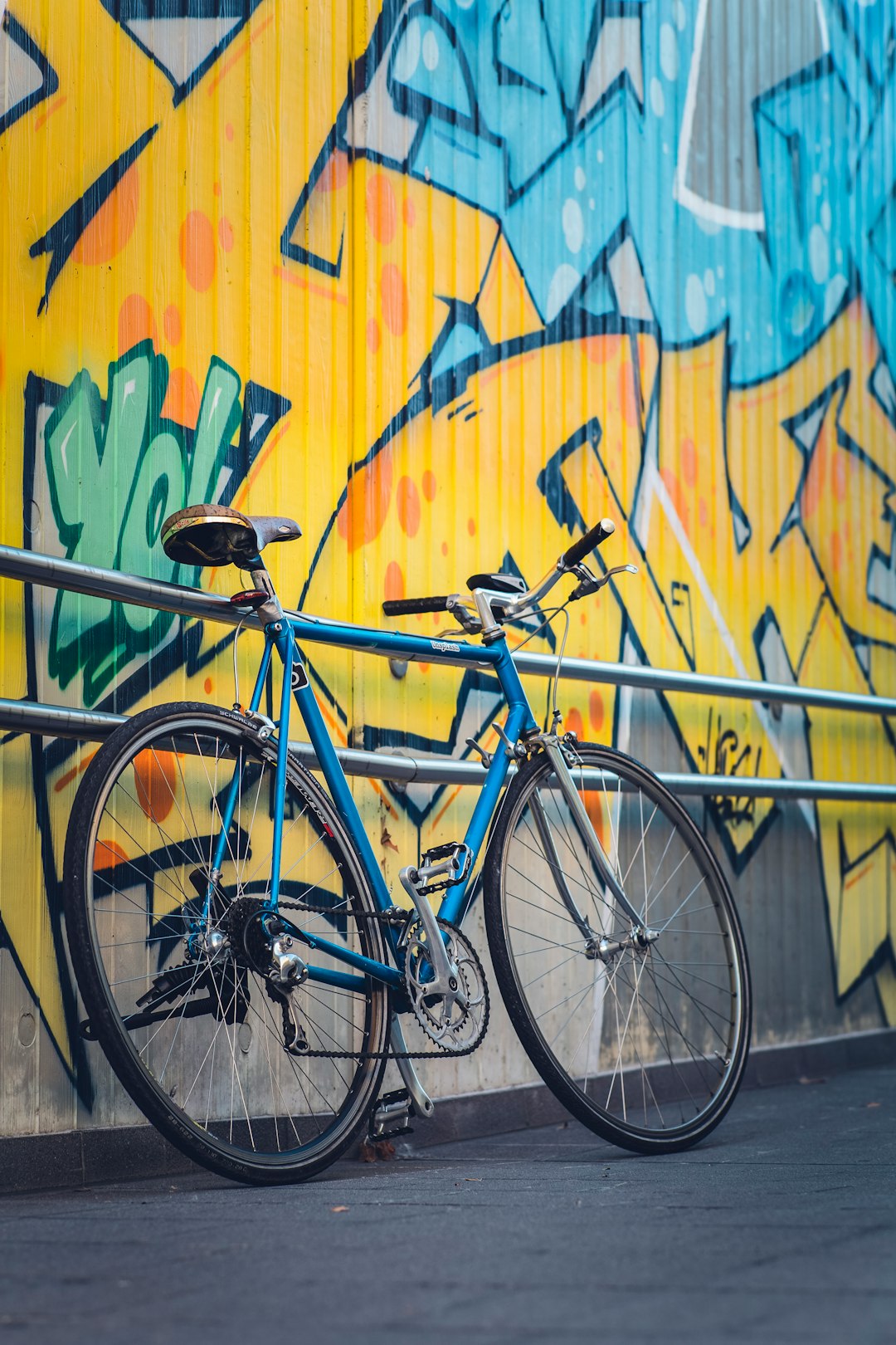 blue city bike beside yellow blue and green wall