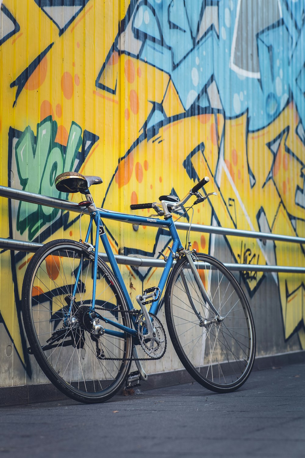 Bicicleta urbana azul junto a la pared amarilla azul y verde