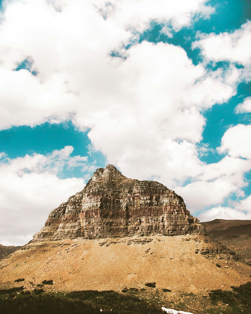 brown rocky mountain under blue sky and white clouds during daytime