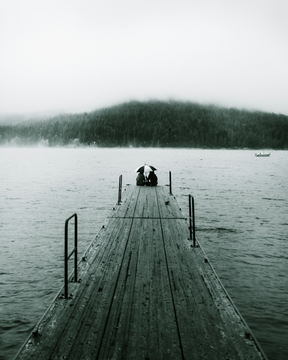 person sitting on wooden dock during daytime