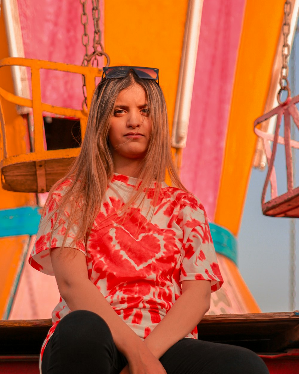 woman in red and white floral shirt sitting on yellow metal chair