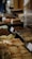 A variety of pastries and baked goods are displayed on a table, including flaky pastries and loaves. There are also bananas and various other pieces of bread and confections, with some items labeled with price tags.