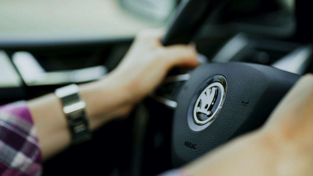 person holding black and gray car steering wheel