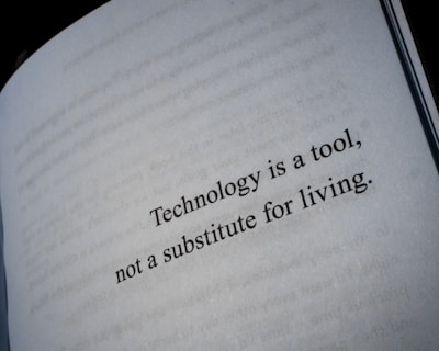 A close-up view of a book page with the text 'Technology is a tool, not a substitute for living.' printed in black letters.