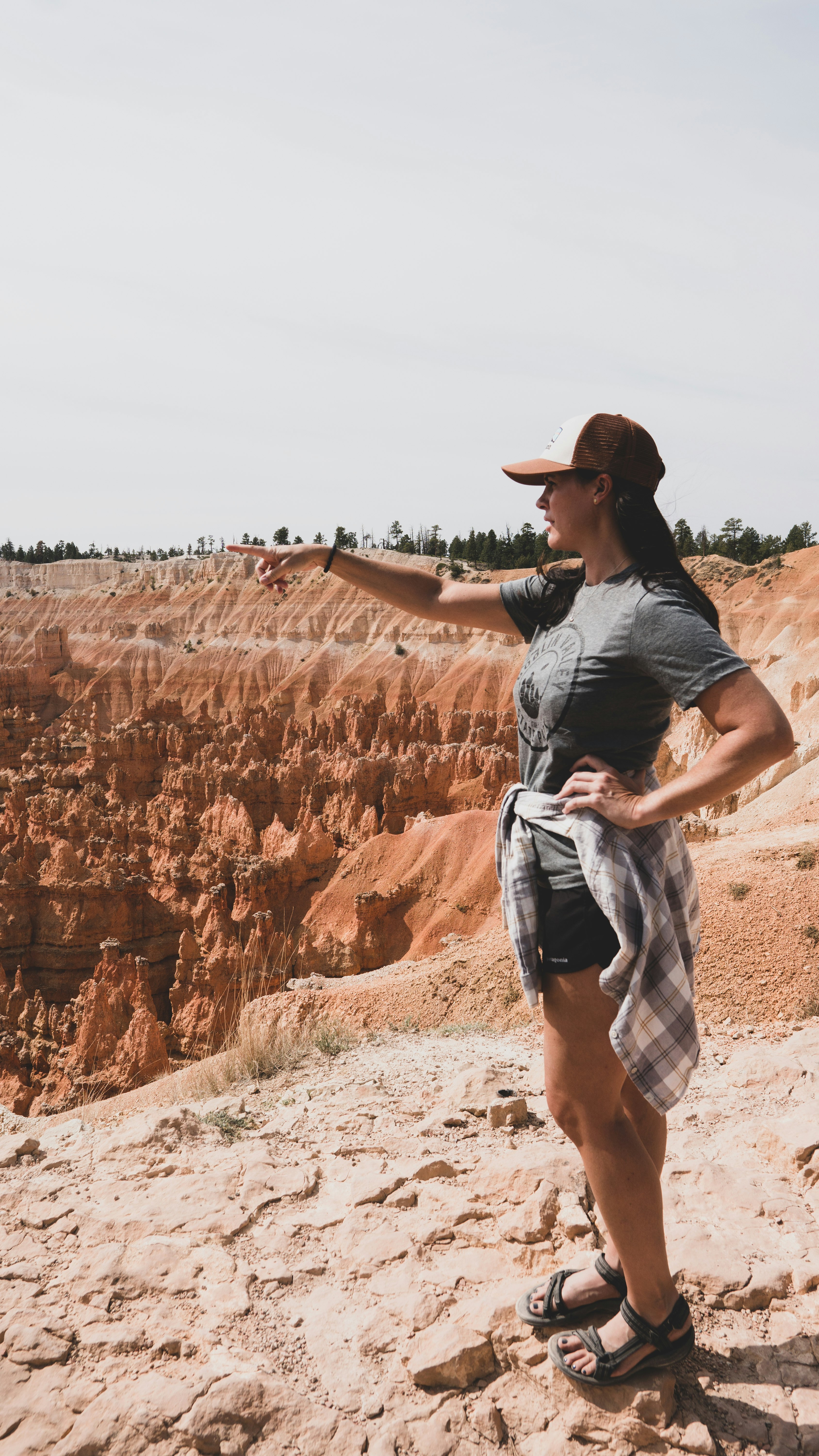 woman in black t-shirt and white skirt standing on brown rock formation during daytime