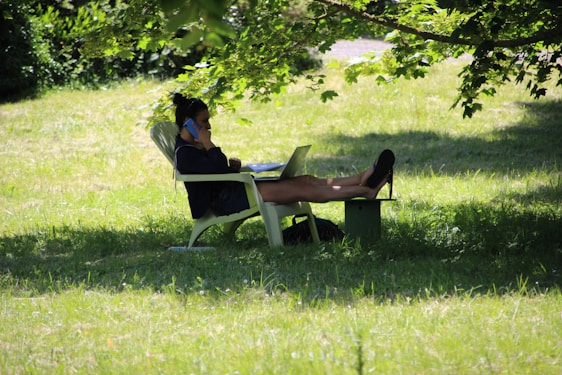 A relaxed person working on a laptop outdoors, symbolizing freedom through online income systems.