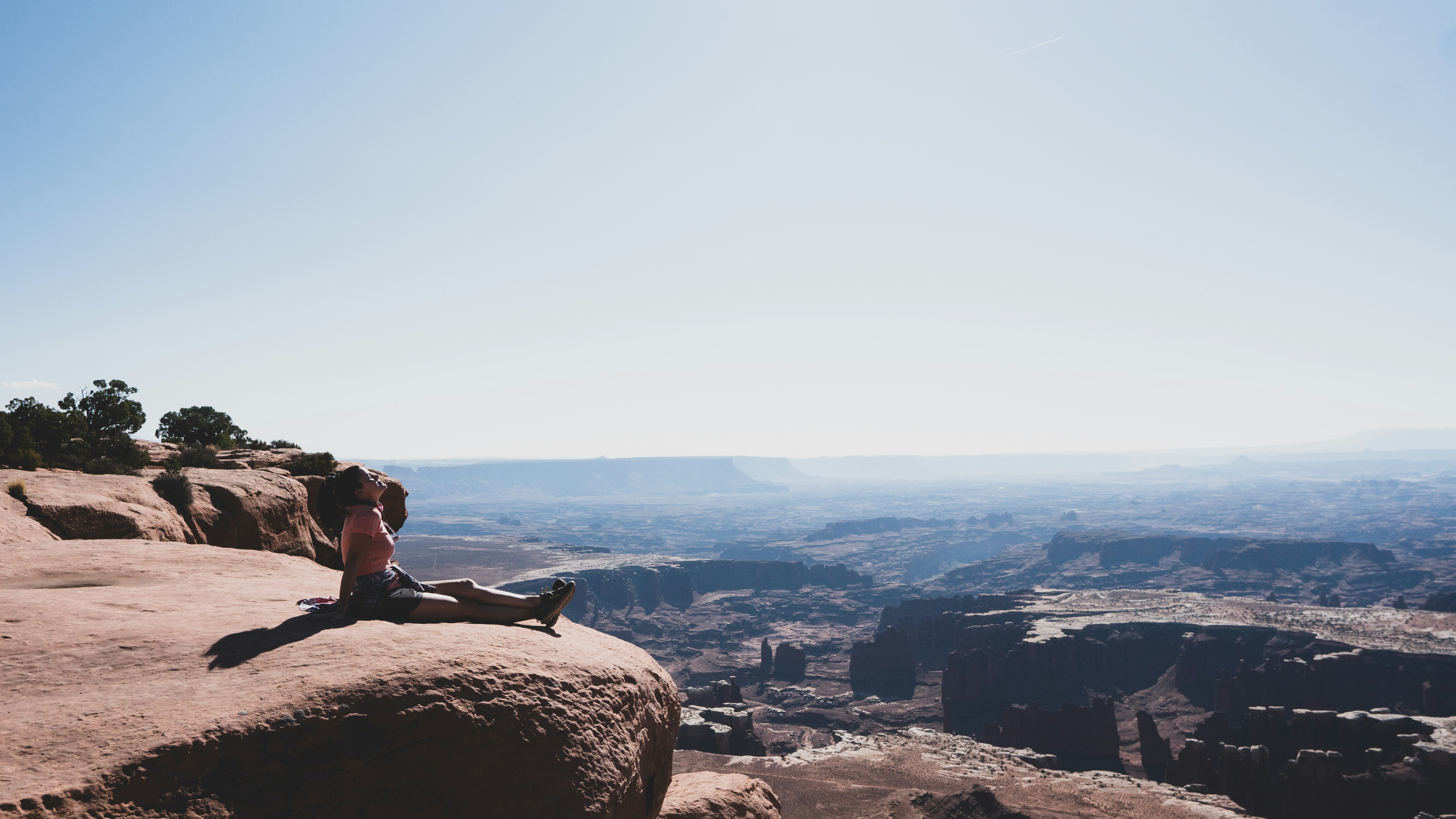 woman in black tank top sitting on brown rock formation during daytime