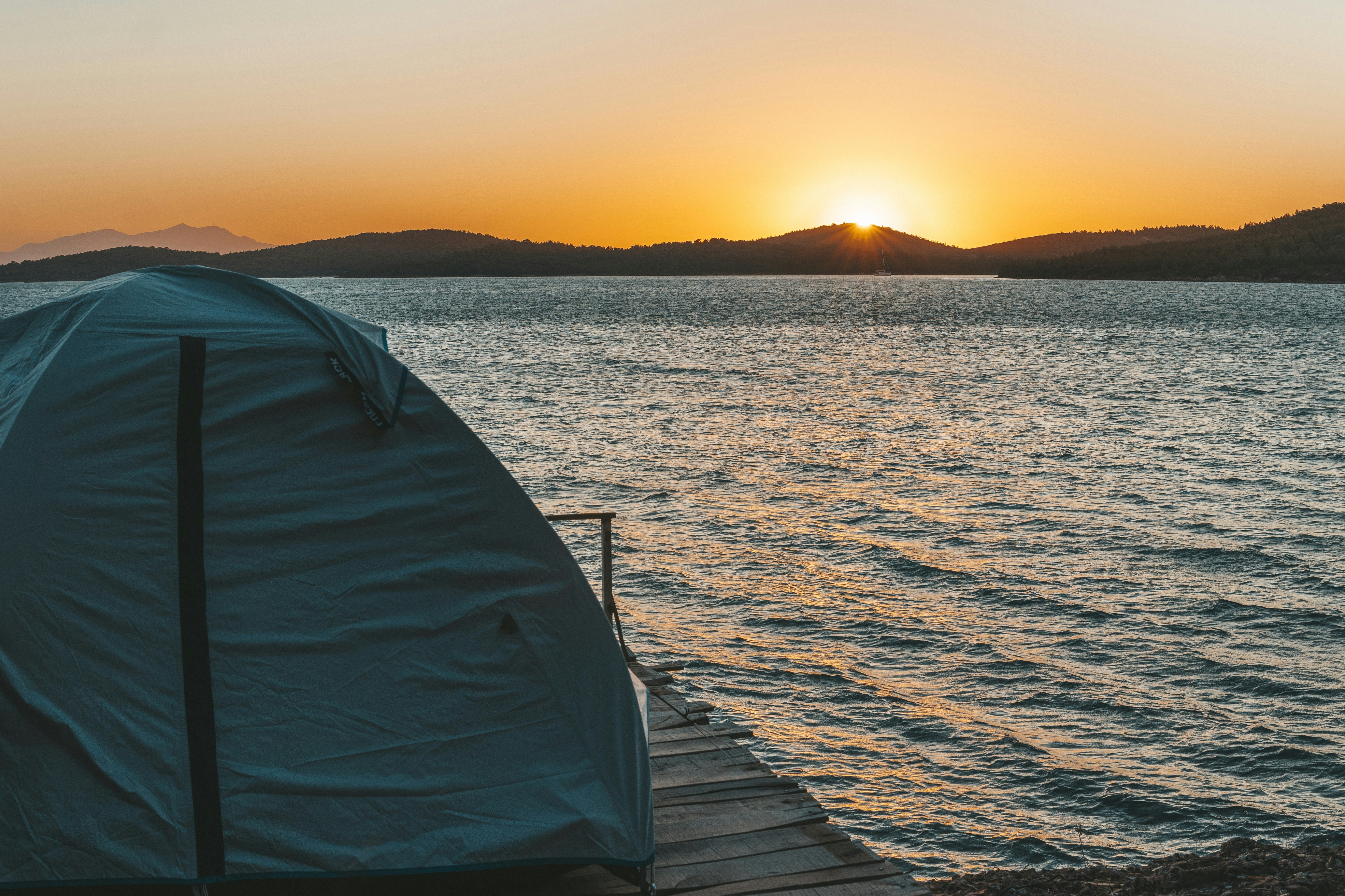 gray tent on brown wooden dock during sunset