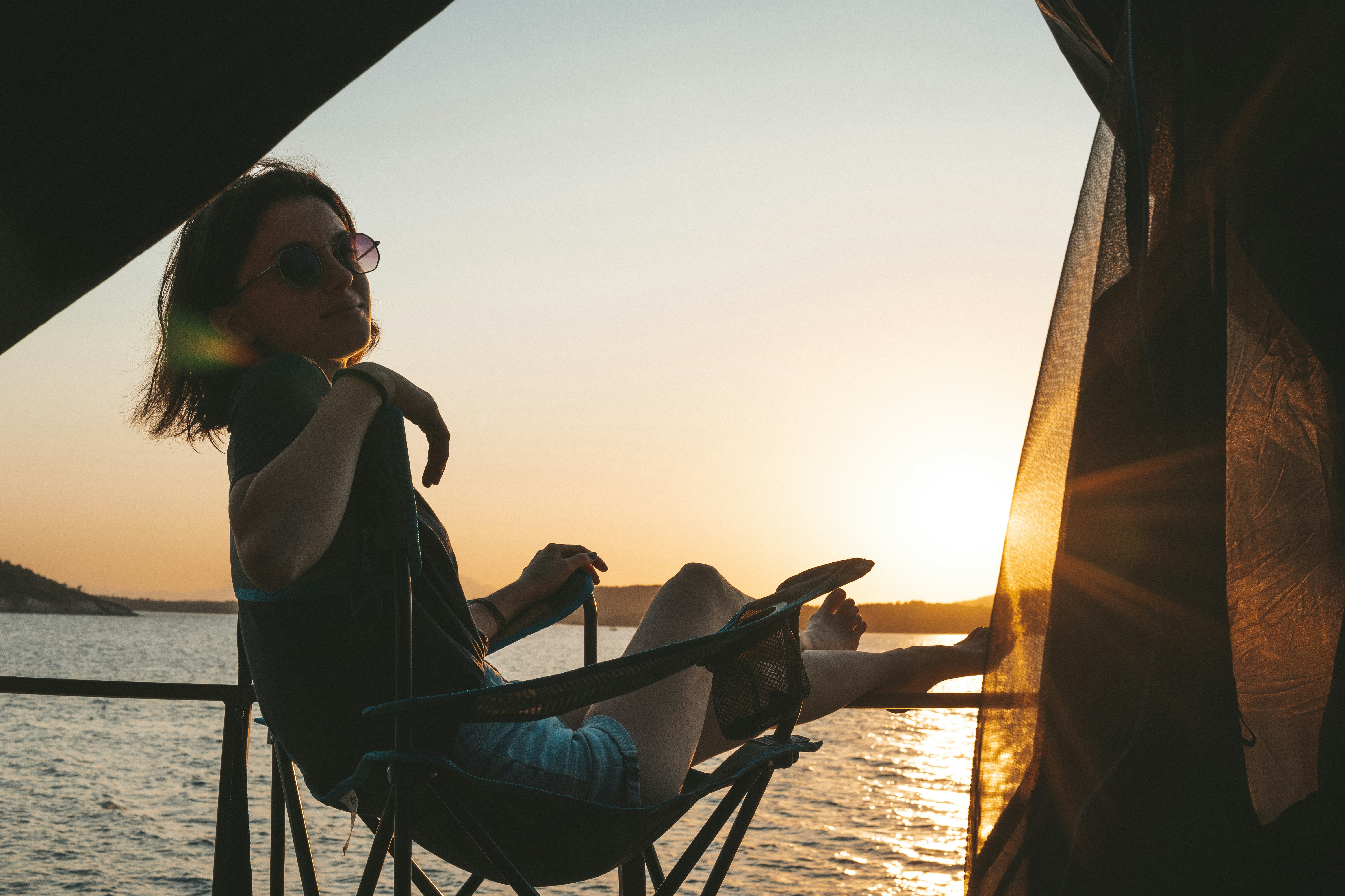 woman in black tank top sitting on chair during sunset