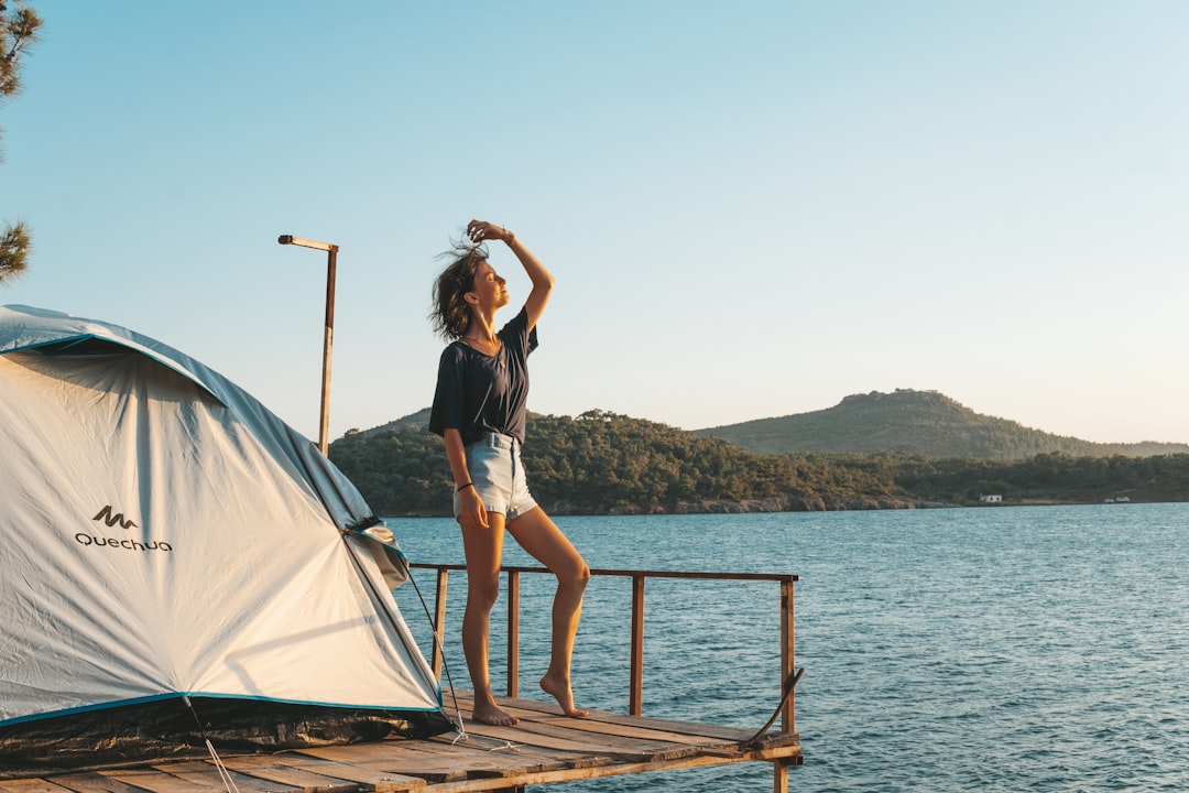 woman in black tank top and white panty standing on brown wooden dock during daytime