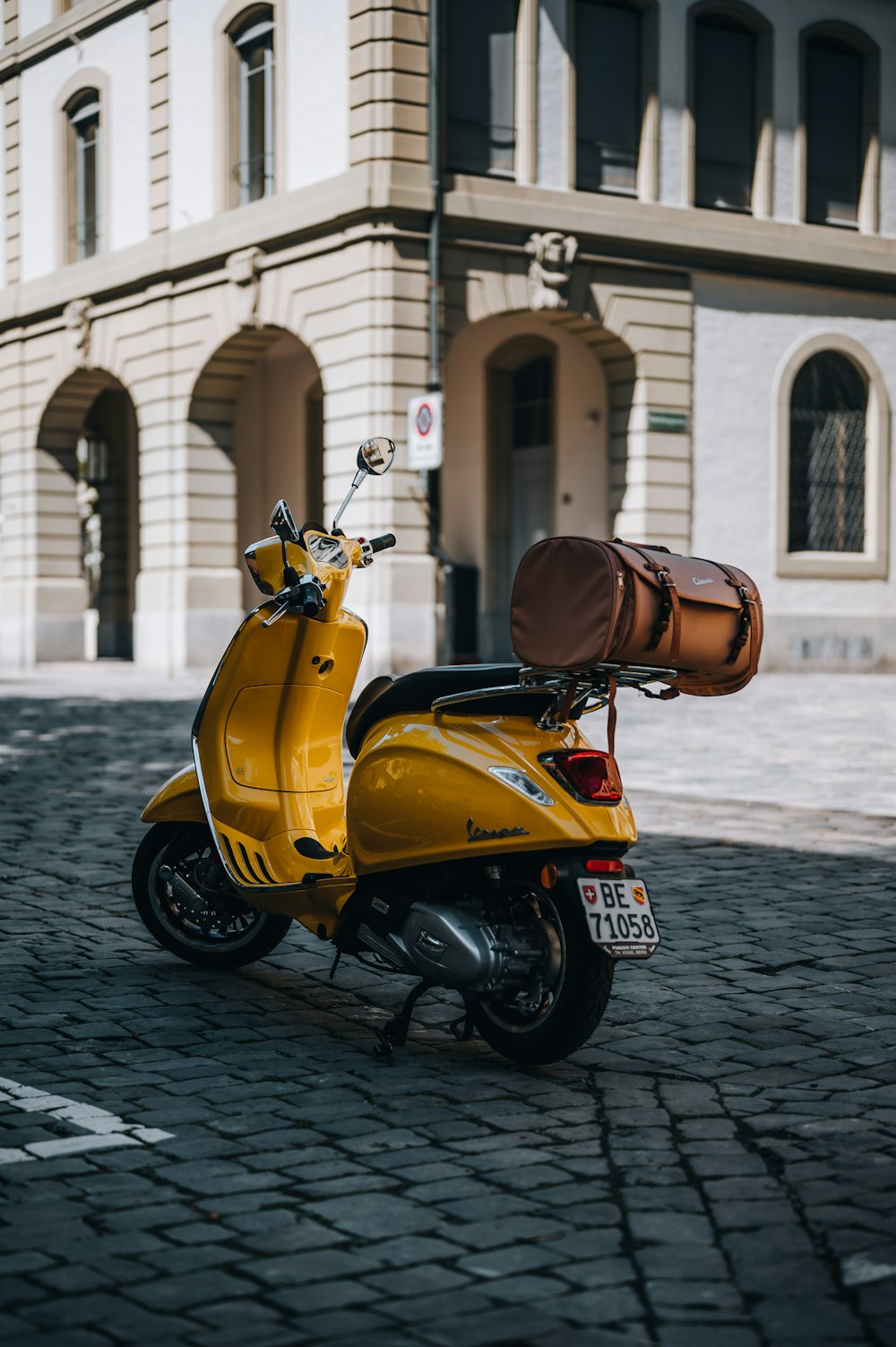 yellow and black motor scooter parked on gray concrete pavement during daytime