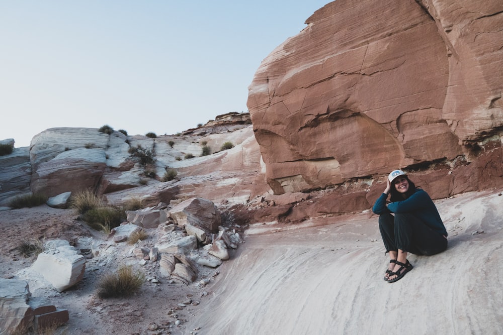 man in blue jacket and black pants climbing on brown rock formation during daytime