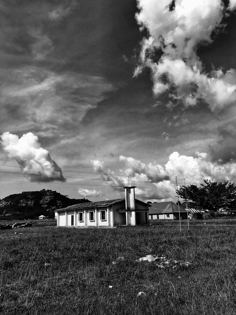 grayscale photo of a white house under cloudy sky