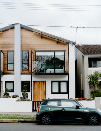 A cozy house exterior with a small garden and car parked in the driveway.